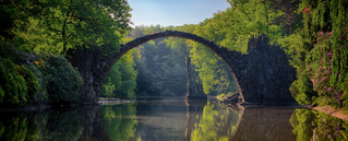 alte Steinbrücke über Fluss umgeben von Wald